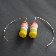 earrings made of small discs on top of each other in yellow and shades of pink by jewellery designer Clare Lloyd.