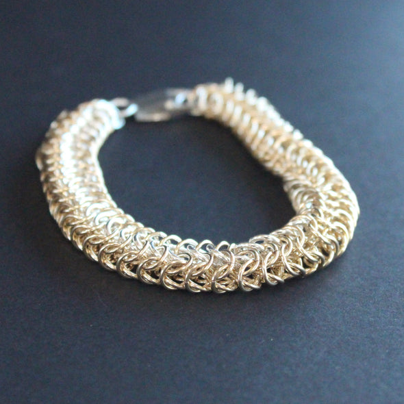 a chainmail tube  bracelet in gold and silver  made by jewellery designer Corrinne Eira Evans.