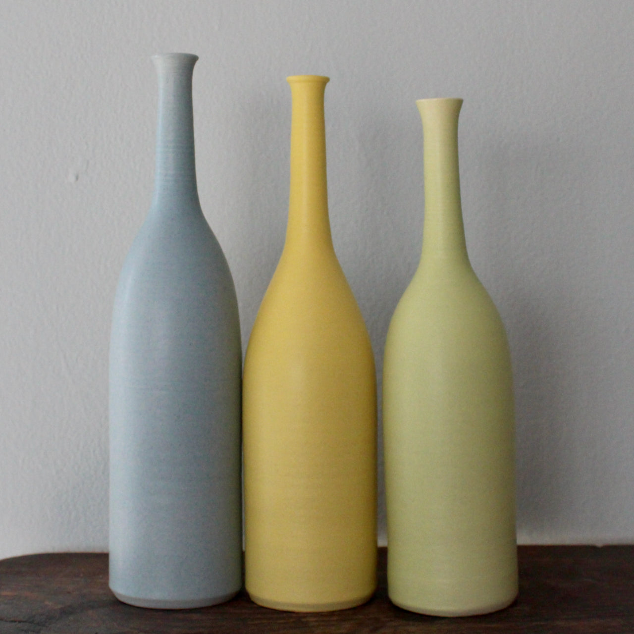 three ceramic bottles in blue, yellow and pale green made by UK ceramic artist Lucy Burley 