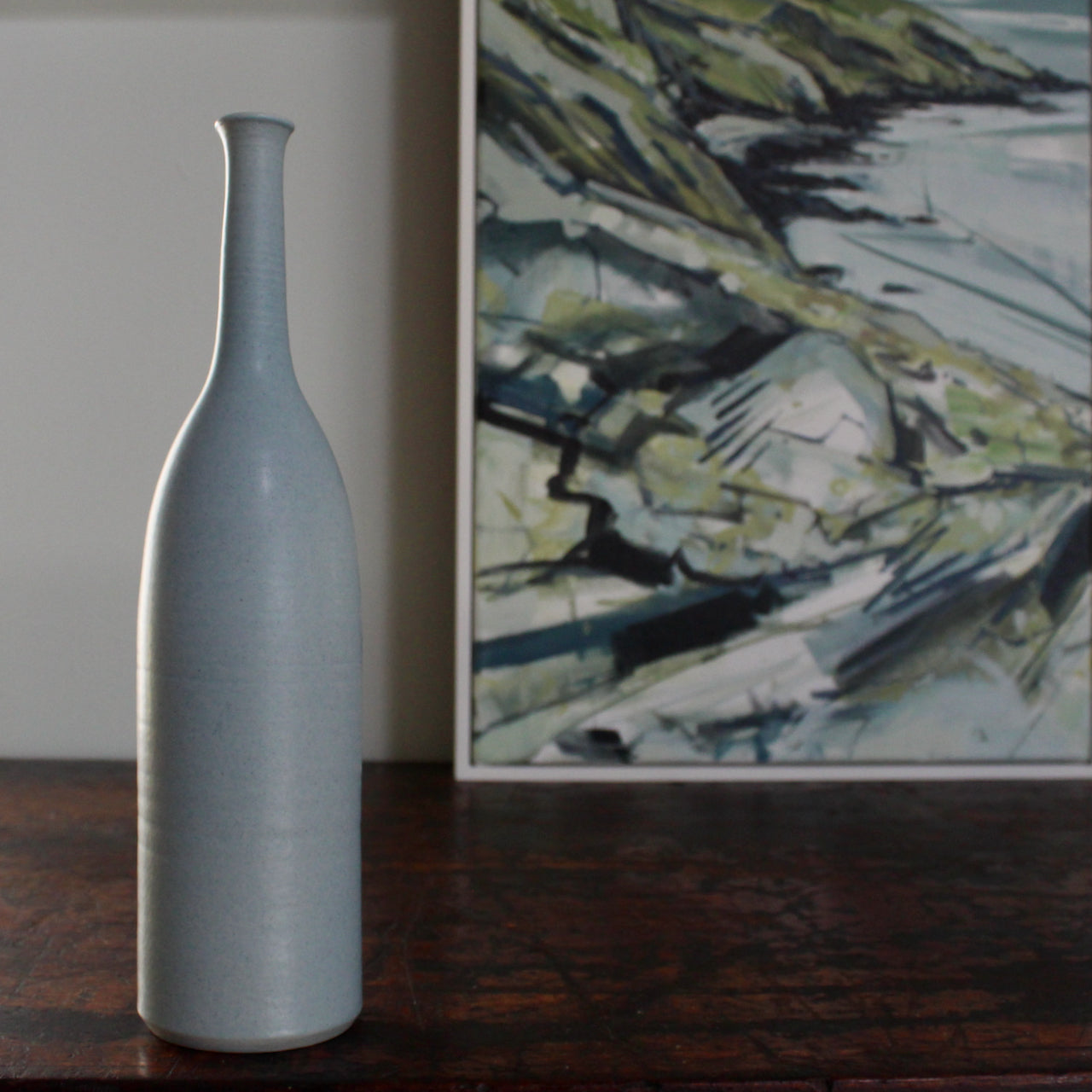pale blue ceramic bottle  made by UK ceramic artist Lucy Burley  next to corner of painting by Cornwall  artist Imogen Bone