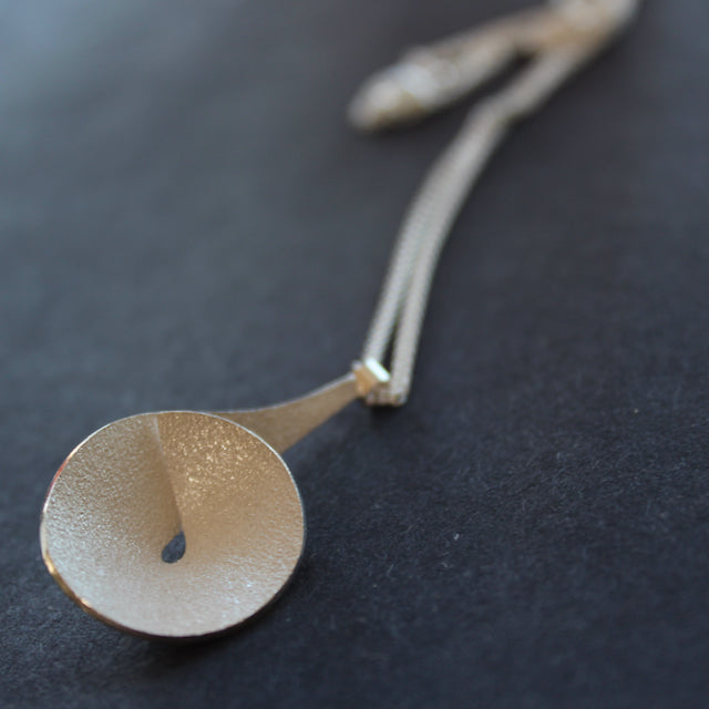 Textured silver curved and circular pendant on a silver chain