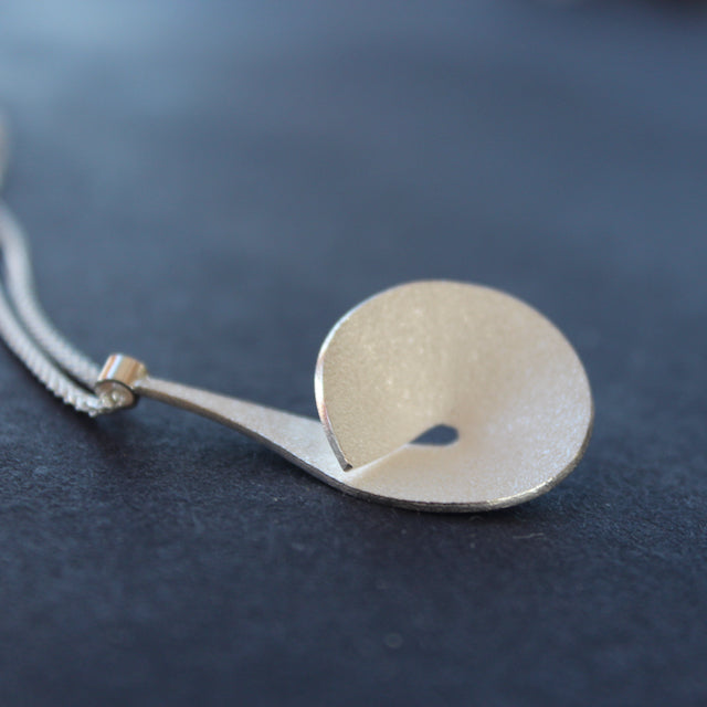 The Byre Gallery pyriform pendant by Beverly Bartlett - it is a Textured silver curved and circular pendant on a silver chain