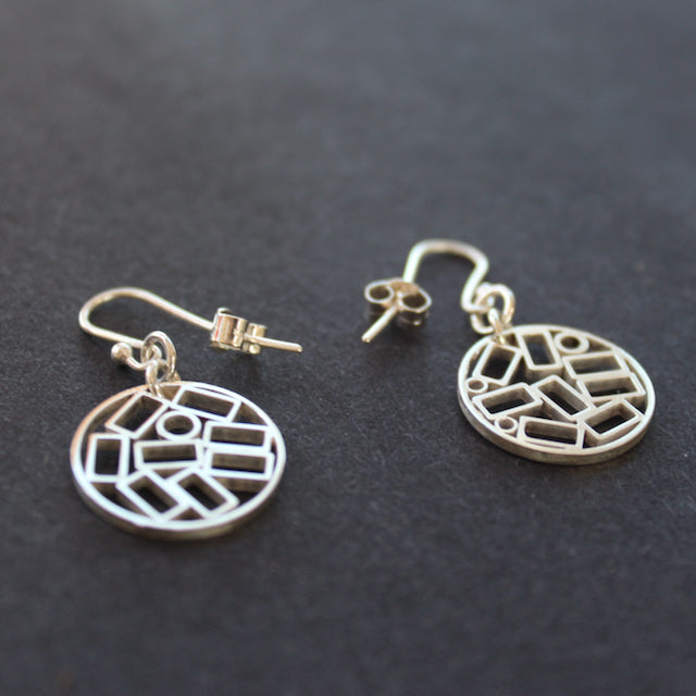 A pair of round silver drop earrings with cut out rectangles making the design at The Byre Gallery they are called Cambium drop earrings by Beverly Bartlett