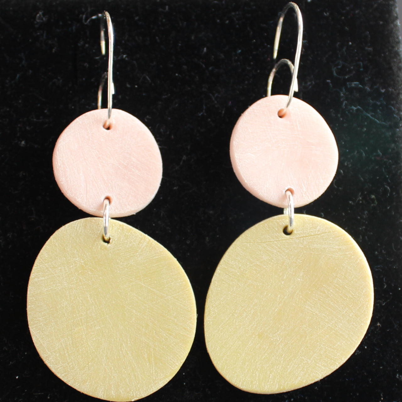 a pair of drop earrings of a large yellow disc with a smaller pale pink on a silver fixing by Clare Lloyd, UK based jewellery designer.
