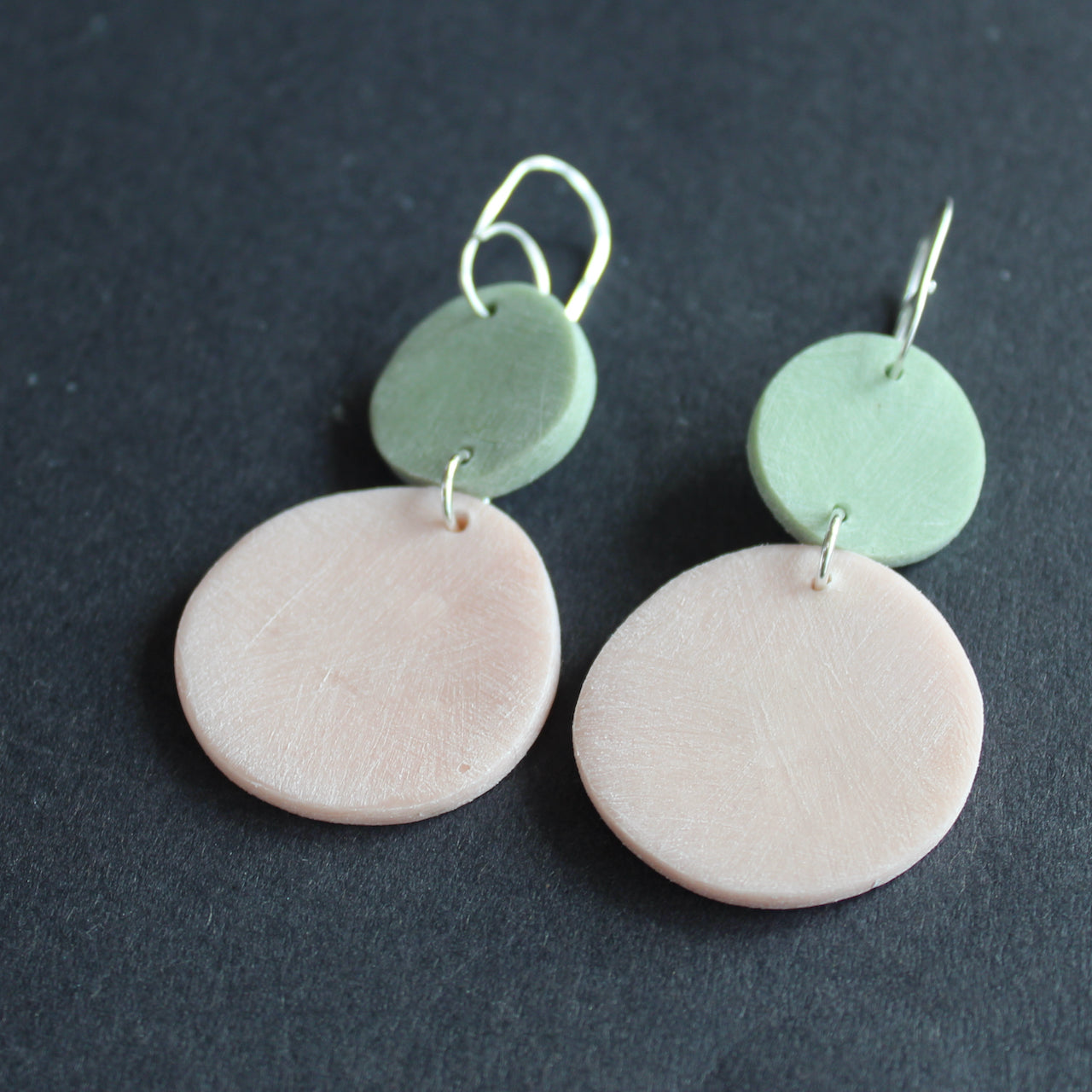 pair of earrings of a pink disc and smaller mint disc made by Clare Lloyd