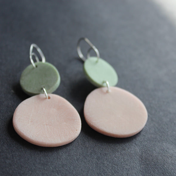 a pair of earrings of a pink disc and smaller mint disc made by Clare Lloyd.