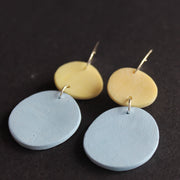 a pair of earrings made by UK jewellery designer Clare Lloyd of blue disc and smaller yellow disc.