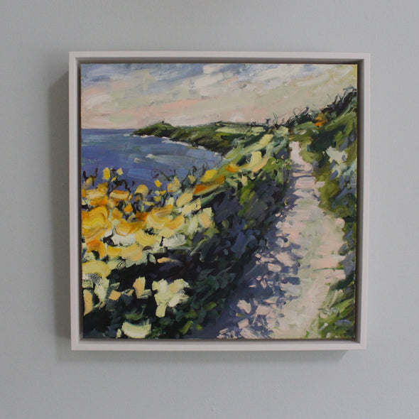 a framed painting by artist Jill Hudson of the coast path and looking towards Rame Head in south east Cornwall 