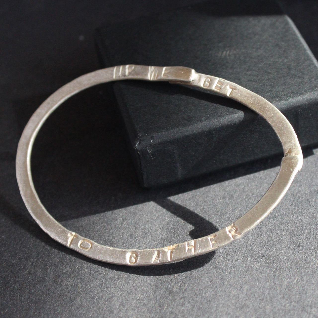 silver bangle with the words up we get to gather embossed on it by jeweller Lizzie Weir of Anatole Design