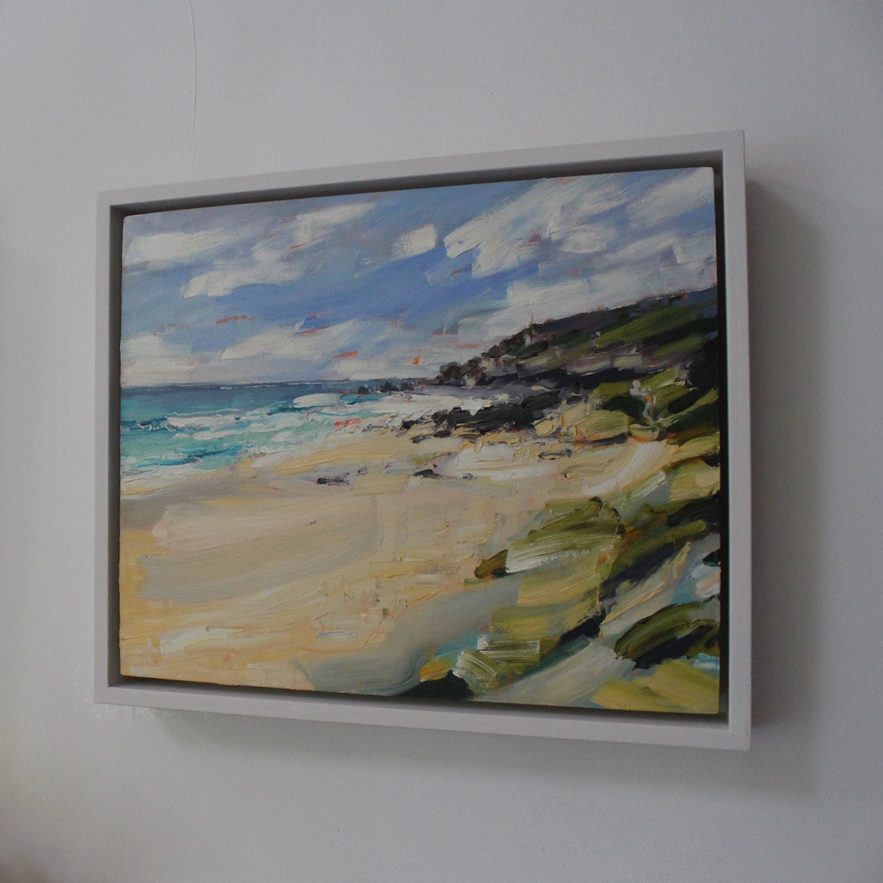 a framed painting of a Cornish beach with pale sand and dark cliffs by Jill Hudson, Cornwall artist