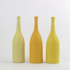 A trio of Lucy Burley ceramic bottles in shades of yellow  sitting on a white background