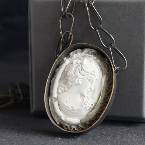 A cameo necklace made from blackened brass and cement by Amy Stringer