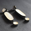 A classic pair of earrings made from blackened brass, cement and a silver pin by Amy Stringer