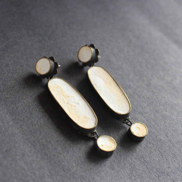 A classic pair of earrings made from blackened brass, cement and a silver pin by Amy Stringer