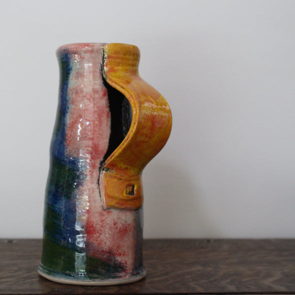 a ceramic jug in blue and red glaze with an orange handle by UK potter John Pollex