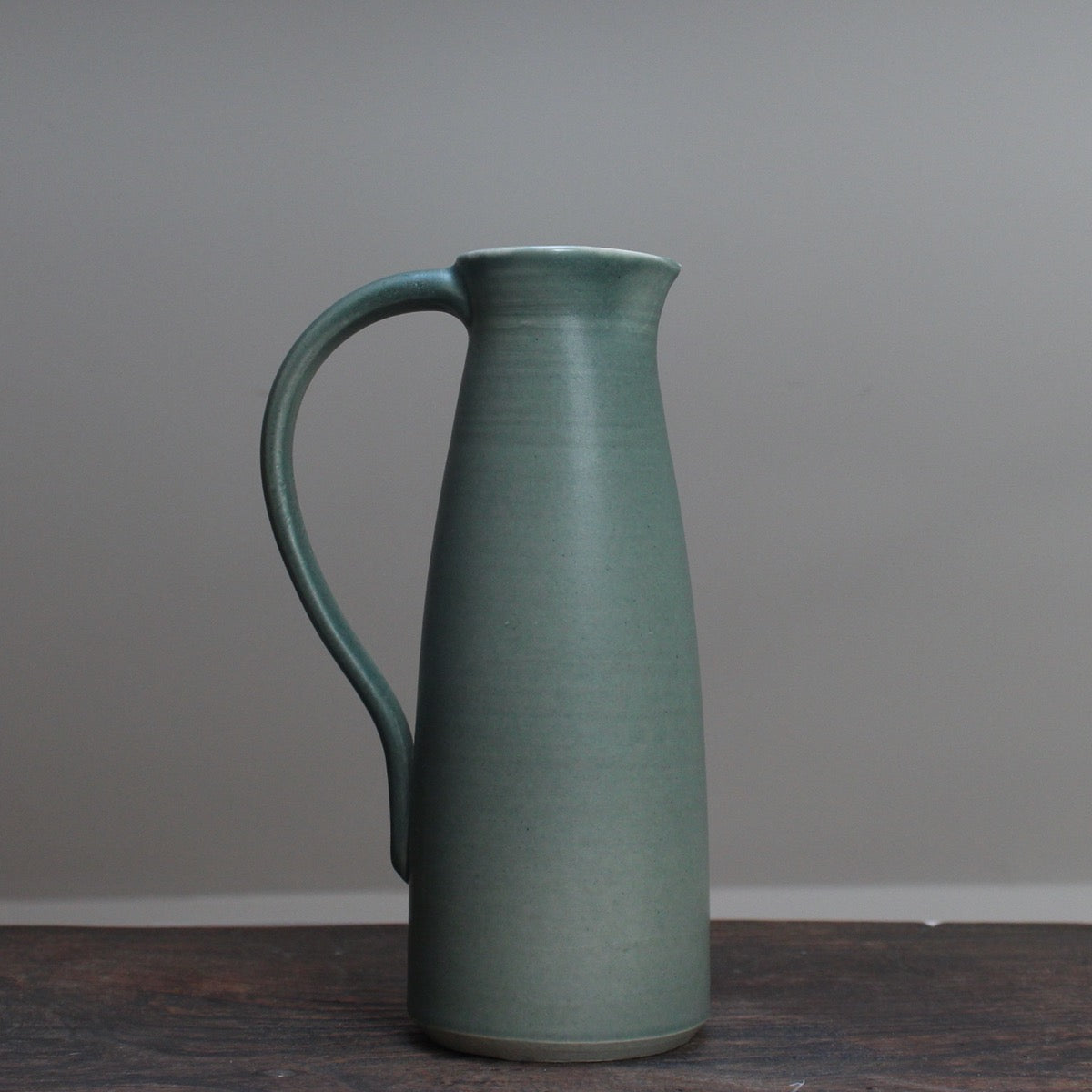 Olive green ceramic jug with handle by Lucy Burley on wooden table at the Byre Gallery 