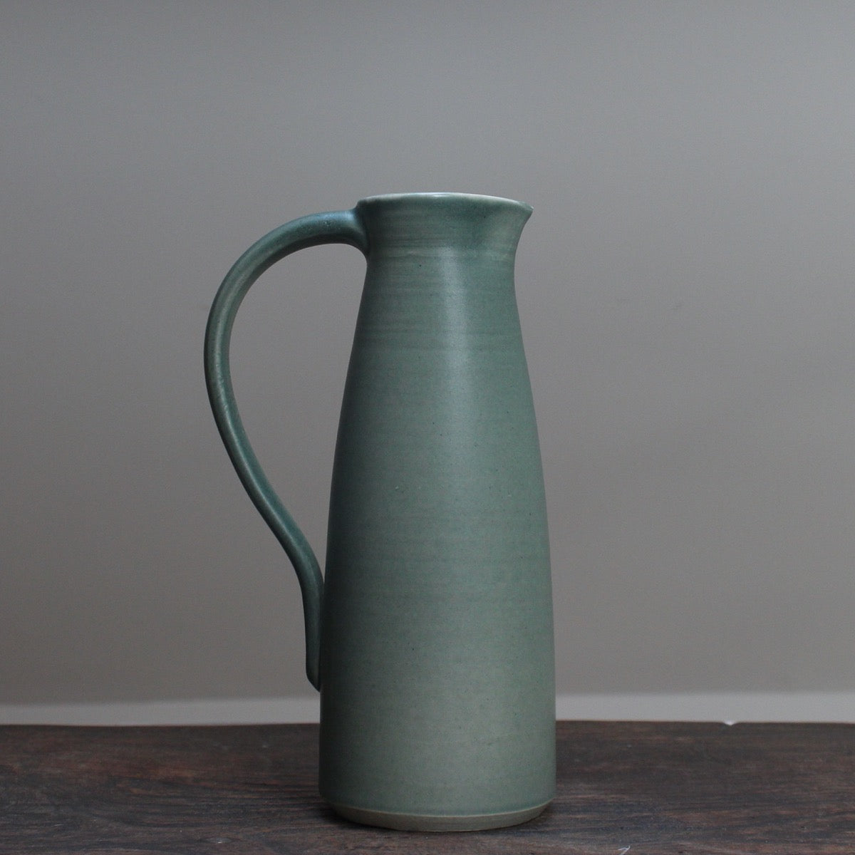 Olive green ceramic jug with handle by Lucy Burley on wooden table at the Byre Gallery