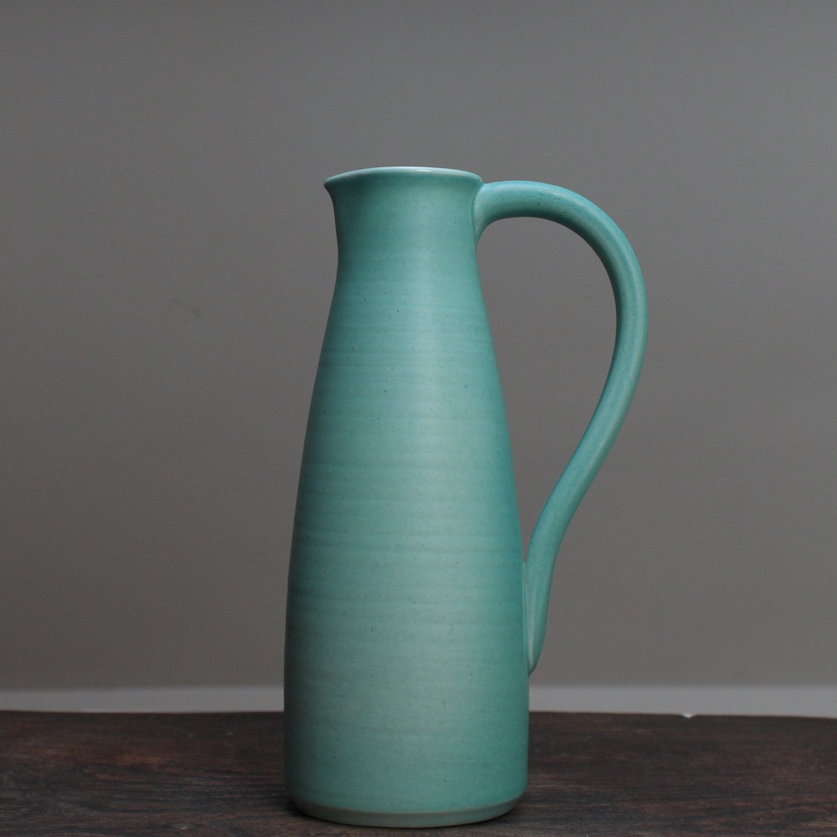Duck egg ceramic jug with a handle by Lucy Burley on a wooden table at the Byre Gallery