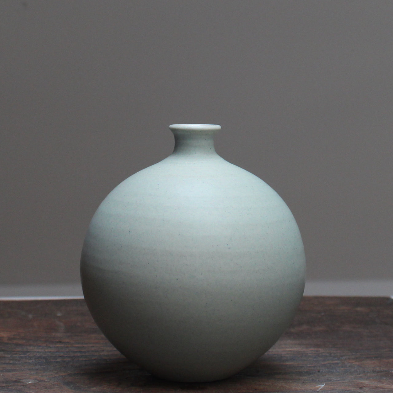Light green round ceramic bottle by Lucy Burley, on a wooden table at the Byre Gallery