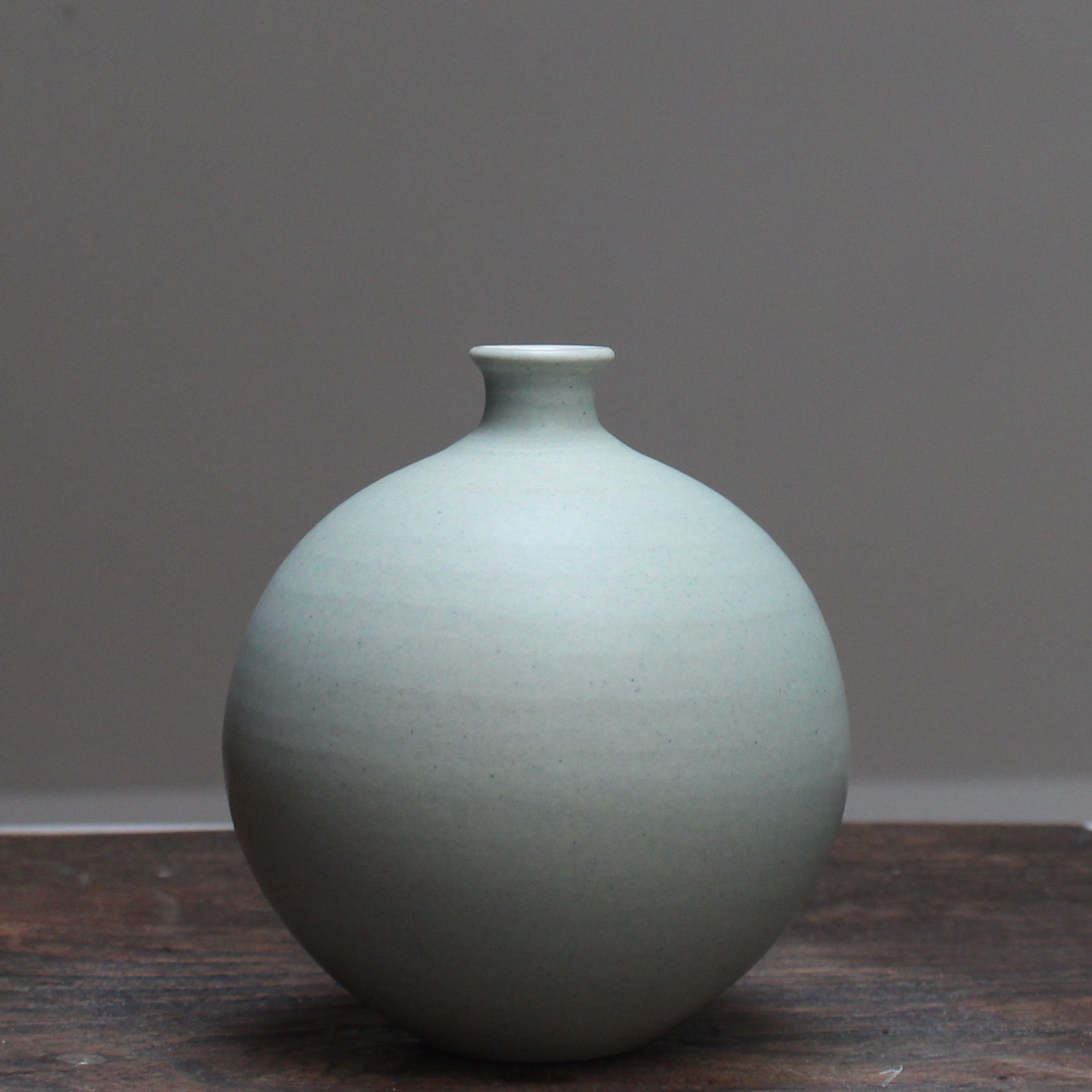 Light green round ceramic bottle by Lucy Burley, on a wooden table at the Byre Gallery 