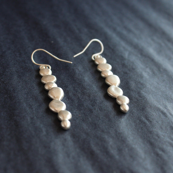 a pair of silver drop earrings of joined together small silver pebbles by jewellery designer Carin Lindberg