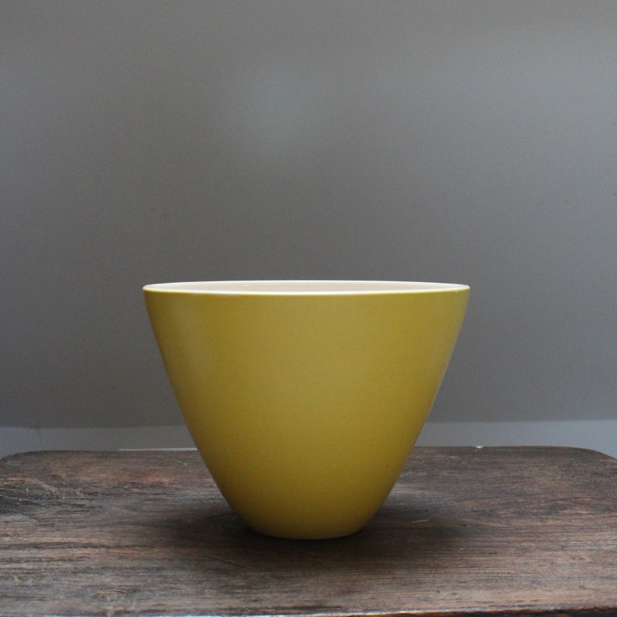 A yellow bowl Lucy Burley on a wooden table