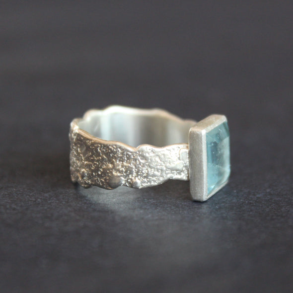 a silver ring by Cornwall Jeweller Carin Lindberg with a square set pale blue aquamarine stone and textured silver band.