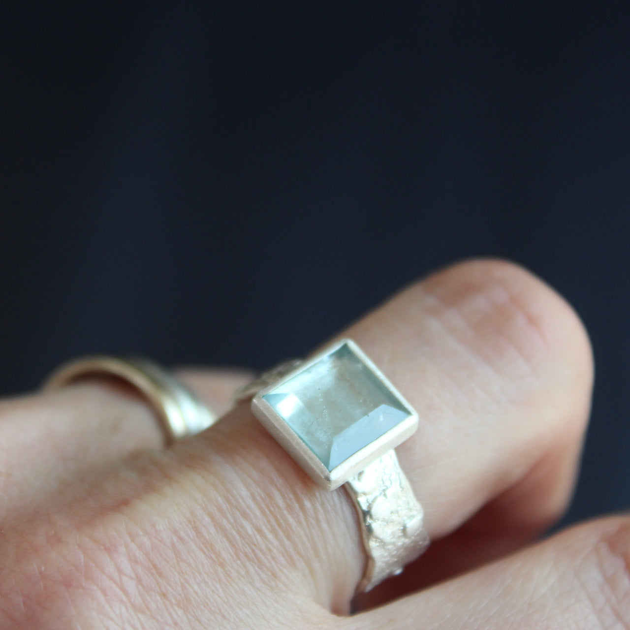 a silver ring by UK Jeweller Carin Lindberg with a square set pale blue aquamarine stone and textured silver band