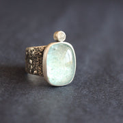 a silver ring with a pale blue aquamarine stone and smaller diamond on a textured silver band by UK jewellery designer Carin Lindberg.