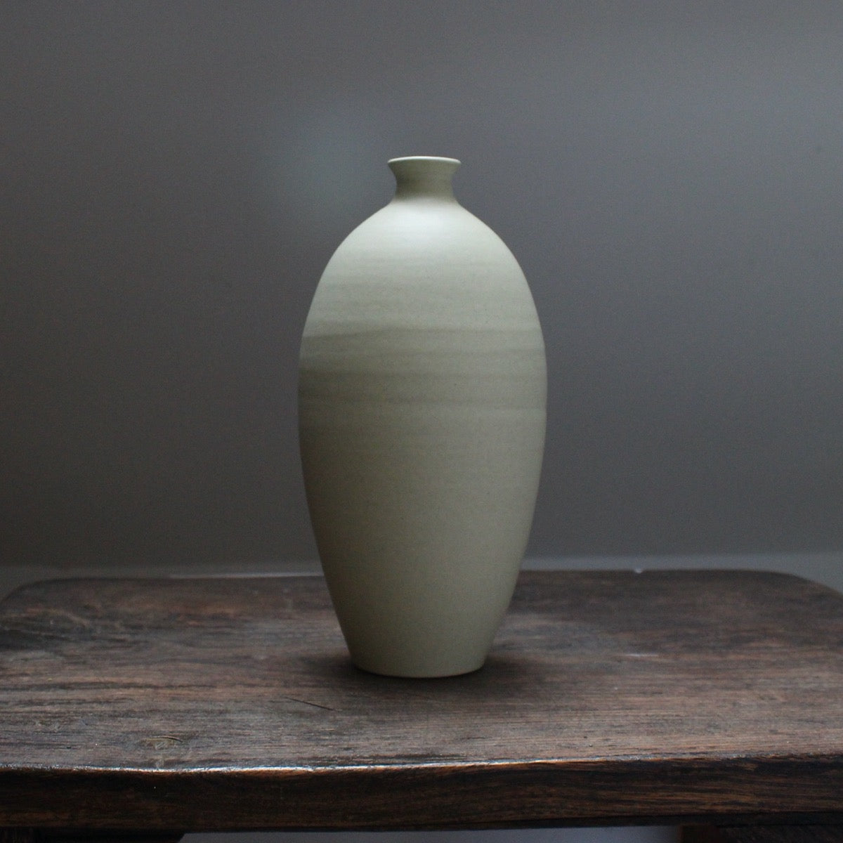 A pale green  ceramic bottle  on a wooden table