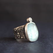 a silver ring with a pale blue aquamarine stone and smaller diamond on a textured silver band by Cornwall jeweller Carin Lindberg.