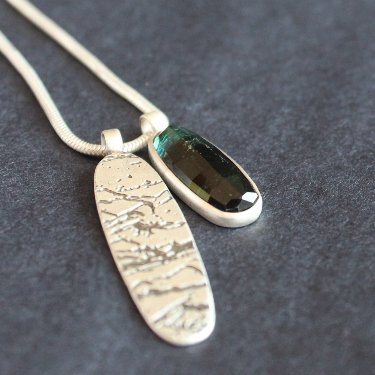double pendant on silver chain of blue green stone and oval shaped silver disc by Cornwall jeweller Carin Lindberg 
