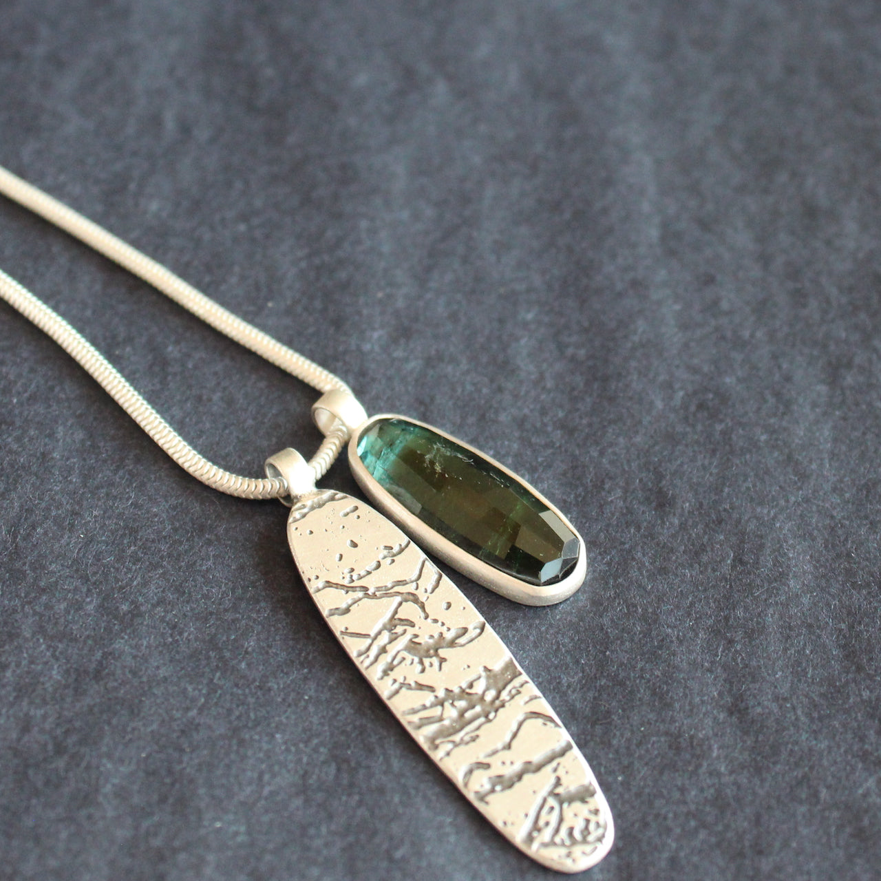 a double pendant on silver chain of blue green stone and oval shaped silver disc by Cornwall jewellery designer Carin Lindberg 