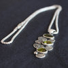 a silver pendant of green stones and silver discs hanging from a silver chain by Cornwall jeweller Carin Lindberg.