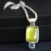 a silver pendant with a bright green stone set in silver oval and small blue stone below by Cornwall jewellery designer Carin Lindberg