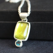 silver pendant with a bright green stone set in silver oval and small blue stone below by Cornwall jewellery designer Carin Lindberg.