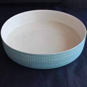 a shallow round ceramic serving dish with blue cross hatch design by Kathryn Sherriff of By the Line Pottery.