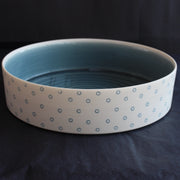 a porcelain serving dish by Kathryn Sherriff of By the Line Pottery with a blue interior and a blue circle design on the exterior.