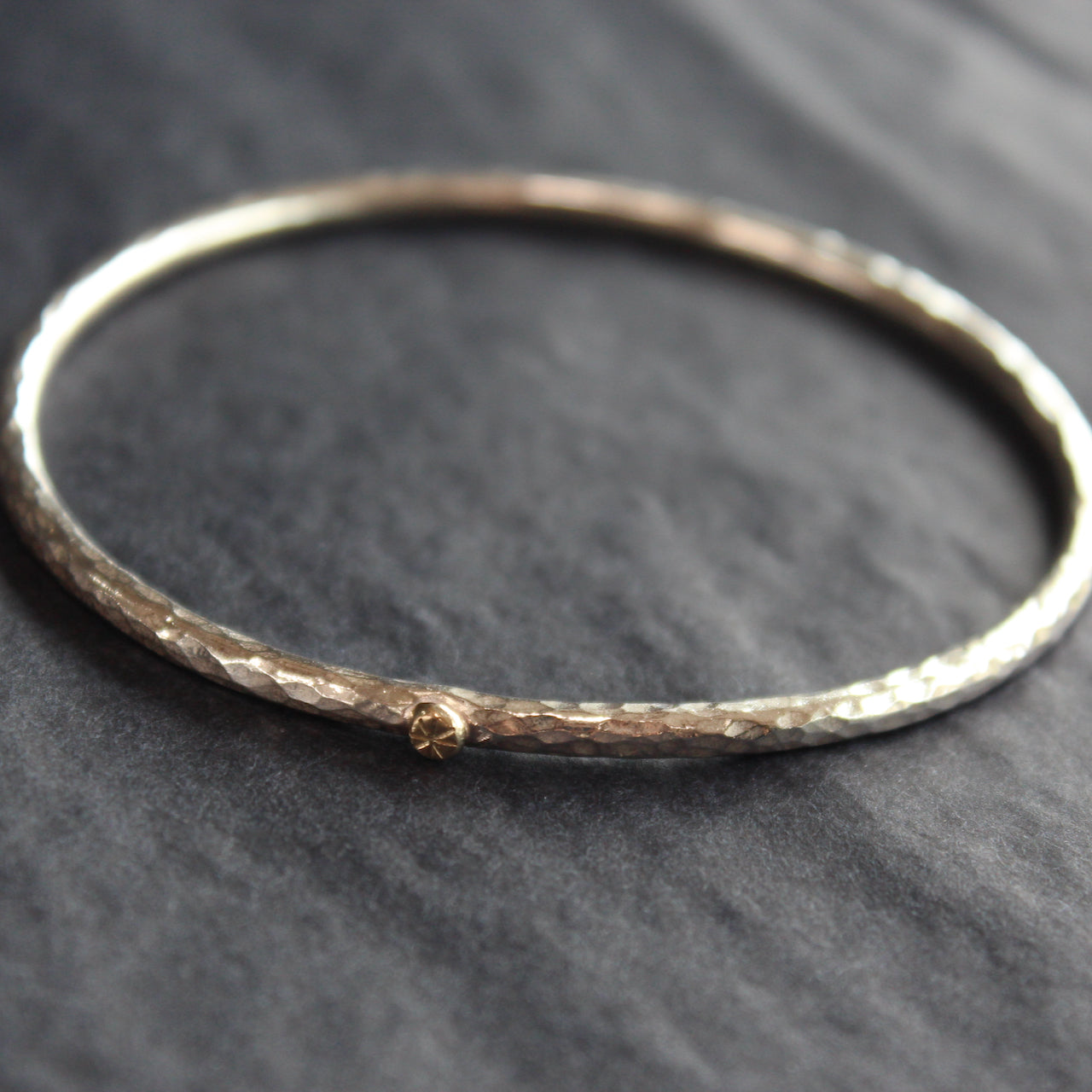 narrow textured silver bangle with small gold dot by Cornwall jewellery designer Lucy Spink
