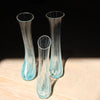 three tall and narrow clear glass vases with turquoise details at the bases by Cornish glass artist Helen Eastham 
