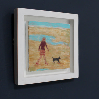 framed painting by Cornish artist Siobhan Purdy of a woman with blonde hair walking a black dog on a beach