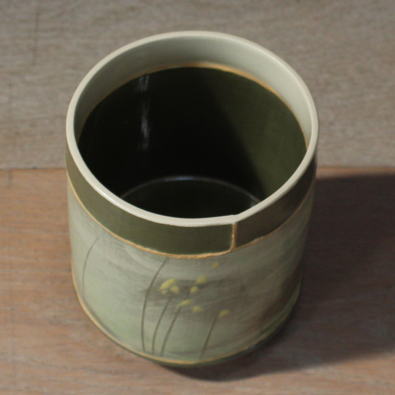 small green glazed ceramic pot with a lighter green and yellow mid section and a dark green interior it was made by UK ceramic artist Emily-Kriste Wilcox