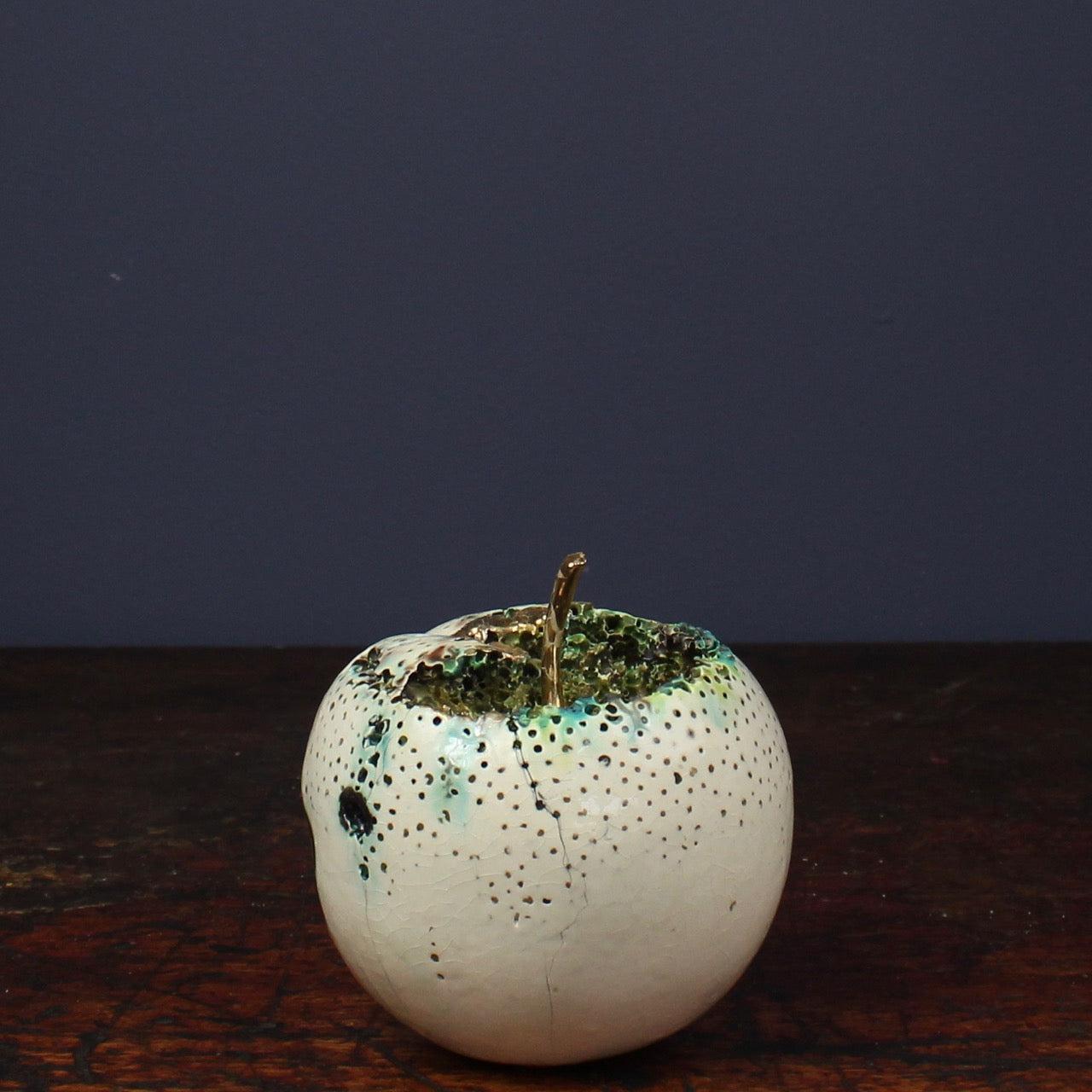 large ceramic white apple with a gold stalk and glaze effects by Remon Jephcott a Cornish based ceramic artist 