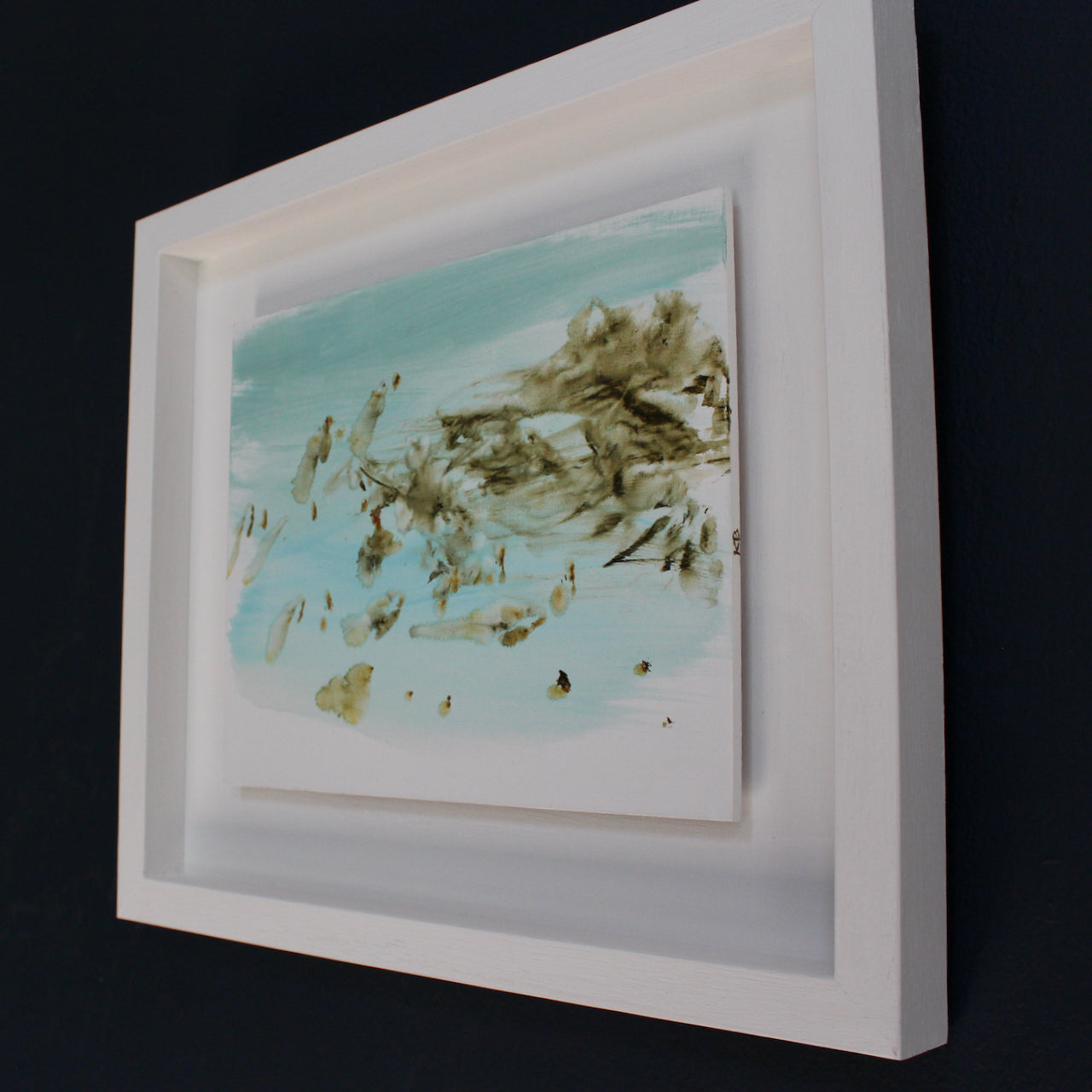 a framed pale blue, white and brown abstract Katy Brown painting of flotsam on a sandy beach