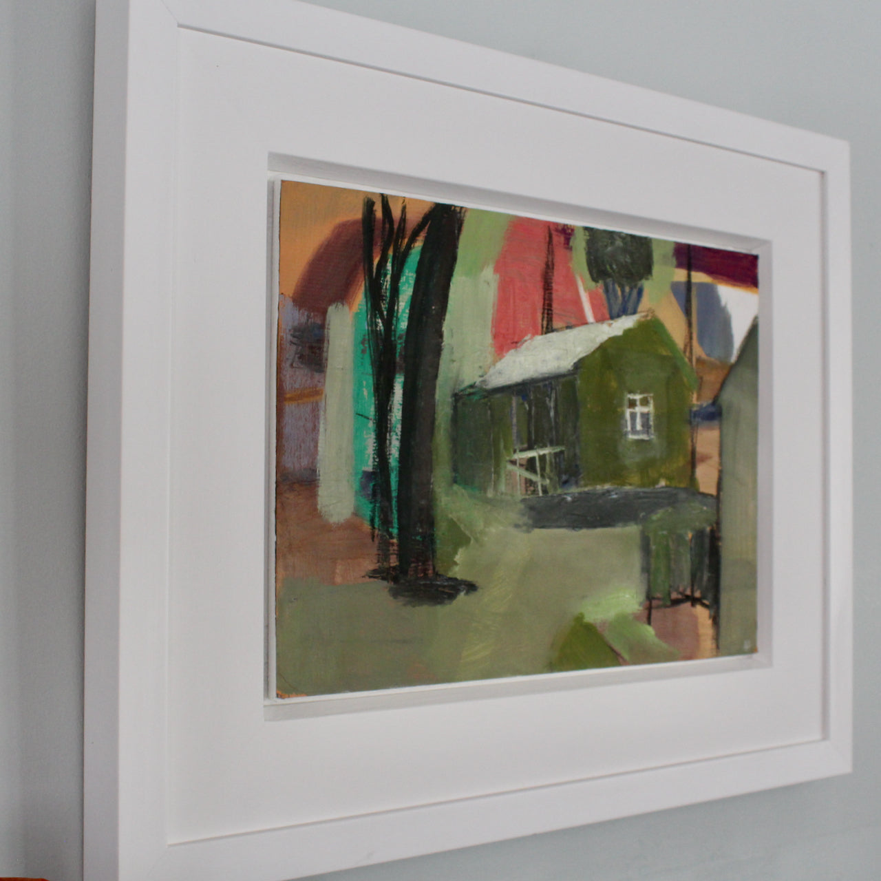 an oil painting in a white frame by Cornwall artist Heath Hearn of a green shed with a white roof in the clearing of some trees 