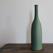 green glazed ceramic bottle on a wooden table it's by UK ceramicist Lucy Burley 