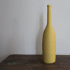 yellow ceramic bottle on a wooden table it's by UK ceramicist Lucy Burley 