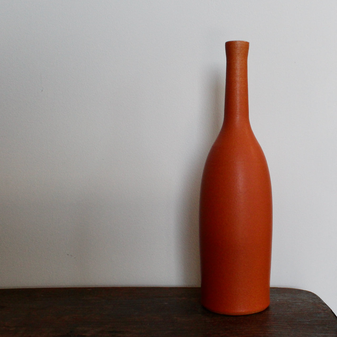 an orange coloured ceramic bottle by UK ceramicist Lucy Burley. 