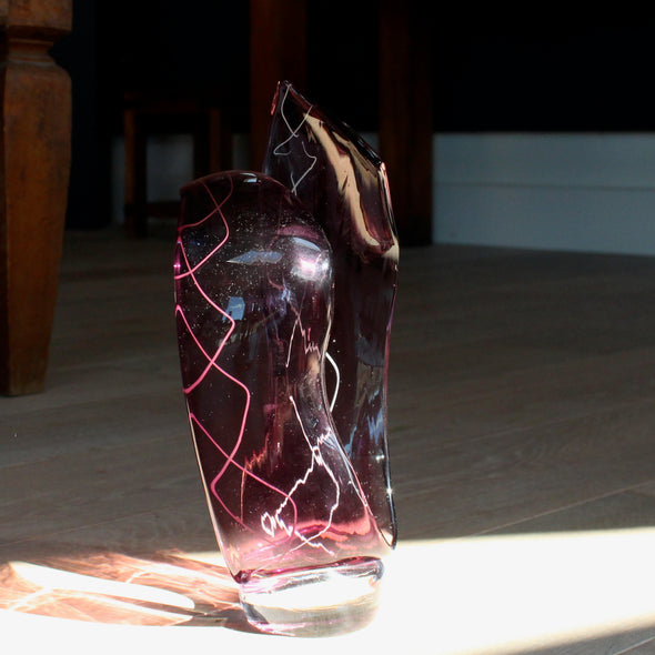 a deep pink glass sculpture with white decoration by glass artist Benjamin Lintell