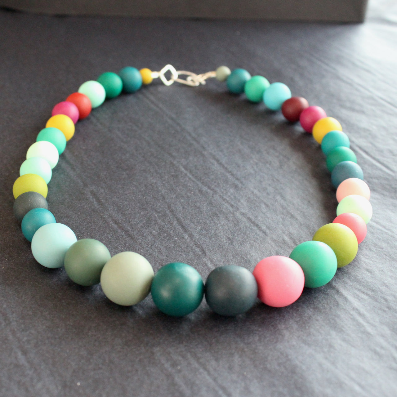 a Claire Lloyd necklace of round beads in greens, pinks, blues and yellow.
